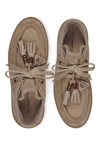 Paire de mocassins en daim beige avec des pompons, des perles et des lacets épais noués en nœuds, vus de dessus sur fond blanc.