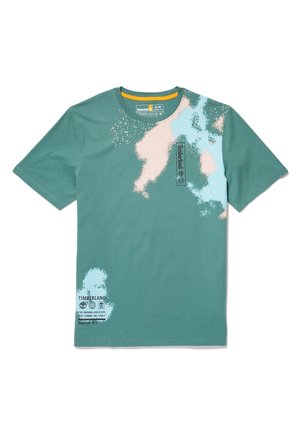 Maglietta Timberland verde a maniche corte con design astratto di schizzi di vernice beige e azzurro chiaro e testo del logo nero sul petto e sull'orlo.