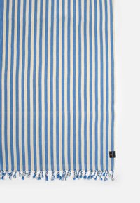 Cotton beach towel featuring alternating blue and cream stripes, finished with blue tassels along the edges. Large rectangular shape.