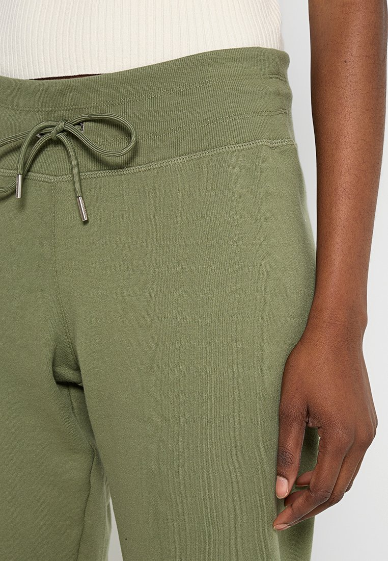 Pantaloni tuta verde oliva con vita a coste, cordino regolabile e texture liscia; i polsini si restringono alla caviglia.