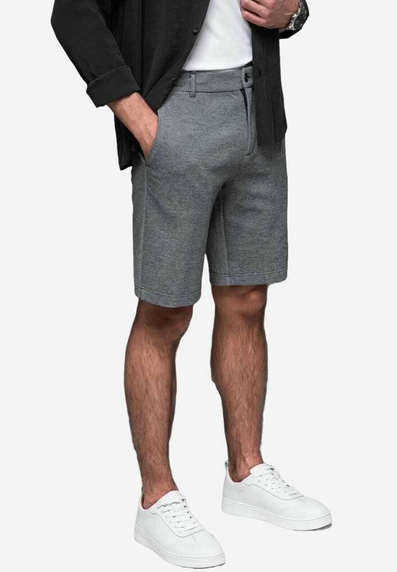 Graue Shorts aus weichem Stoff verfügen über seitliche Taschen und ein tailliertes Design. Kombiniert mit weißen Sneakers für einen lässigen Look.
