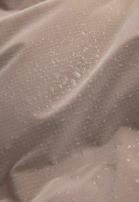 Könnyű bézs színű, vízlepergető anyag texturált hálómintával, amelyen vízcseppek láthatók a felületen. Simítóssága miatt kellemes tapintású.