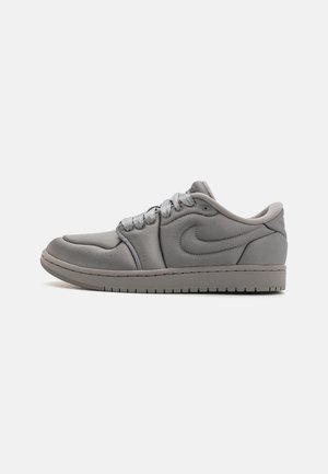 Baskets Nike en gris clair, dotées d'une tige en tissu lisse, d'un bout arrondi et d'une semelle texturée, avec des lacets gris et un logo sur le côté.