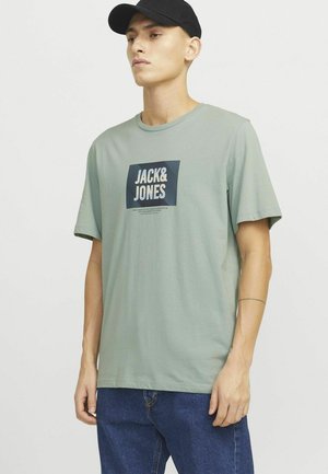 Lichtgroene katoenen t-shirt met een rechthoekig marineblauw ontwerp met de tekst "JACK & JONES", korte mouwen en een ronde hals.