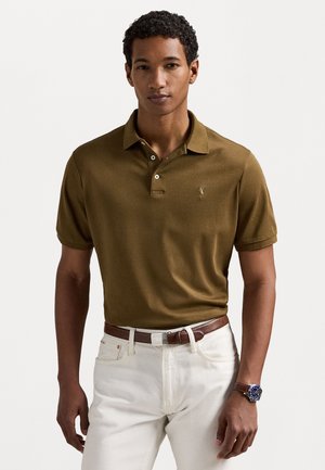 Pruun polo särk klassikalise kraega, kahe nupuga ja väikese logoga vasakul rinnal. Seljas valged püksid ja pruun vöö.