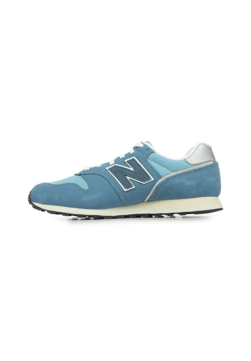 Baskets en suède bleu et mesh avec une semelle blanche, arborant un grand logo "N" noir et un accent argenté au niveau du talon.