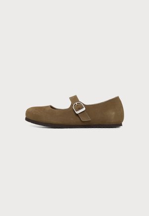 Chaussure Mary Jane plate marron avec une sangle réglable et une boucle argentée sur fond blanc uni.