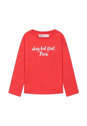 Camiseta de manga larga roja hecha de algodón, con texto blanco que dice "bueno, pero primero, París", y un escote redondo relajado.