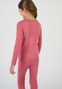 Top in cotone rosa con maniche lunghe e scollatura rotonda, abbinato a leggings rosa coordinati. Tessuto morbido e design aderente.