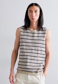 Knit sleeveless sweater featuring alternating horizontal stripes in cream, navy, and purple, with a ribbed neckline and hem.
