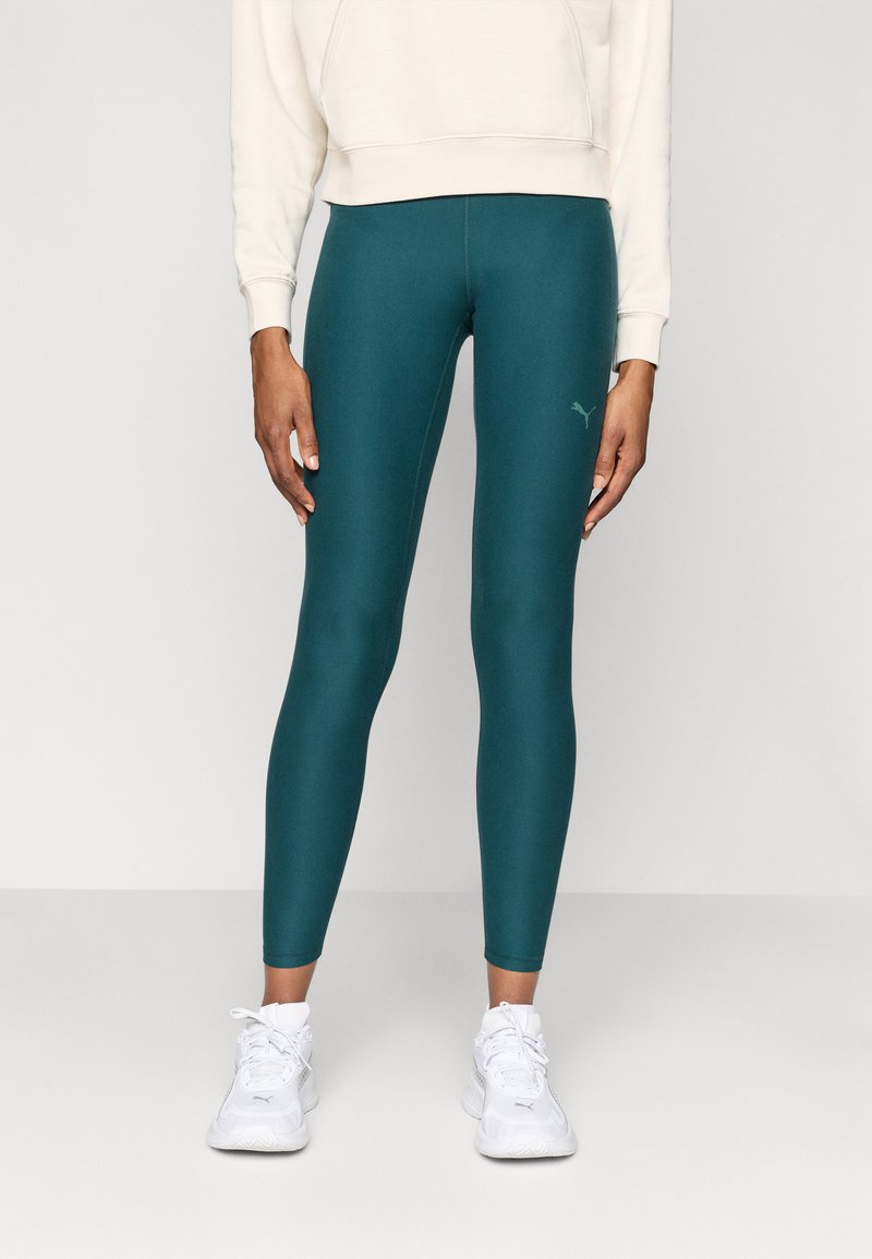 Leggings teal feitos de um tecido elástico com uma textura suave e um design ajustado. Apresenta um pequeno logótipo do lado esquerdo.