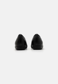 Ballerine nere trapuntate con punta affusolata, materiale in pelle liscia, profilo basso e suola in gomma. Nessun abbellimento o motivo visibile.