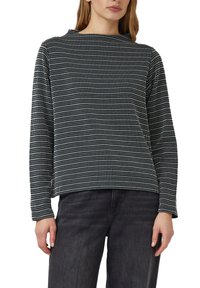 Czarnobiała bluzka z długim rękawem o fakturowanym wzorze z małych kropek, z wysokim kołnierzem i luźnym krojem. W połączeniu z ciemnymi dżinsami.