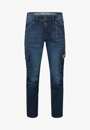Denim cargo jeans in dark blue featuring multiple pockets, a zippered side pocket, and logo patch on the leg. Regular fit with straight leg.