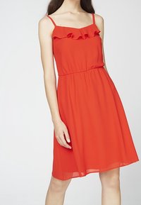 Rotes Chiffonkleid mit dünnen Trägern, Rüschendetail am Ausschnitt, elastischer Bund, A-Linie Silhouette, Saum fällt über das Knie.