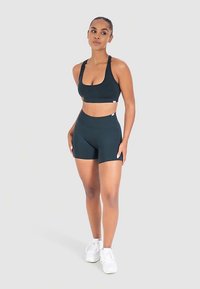 Zwarte sportbeha en bijpassende hooggetailleerde short gemaakt van rekbare stof, met een eenvoudig ontwerp en een gladde textuur.