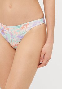 Costum de baie floral, cu un fund de culoare verde mentă deschisă, accentuat cu nuanțe de piersică și lavandă, fabricat dintr-un material neted și elastic pentru confort.