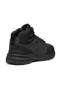 Scarpa nera mid-top con pannelli in pelle sintetica liscia e tessuto, suola in gomma testurizzata e dettagli di cucitura prominenti.