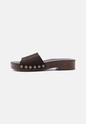 Sandale mule en daim marron avec un petit talon bloc en bois et six clous dorés le long du côté de la bride supérieure.