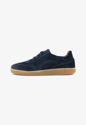 Granatowy zamszowy sneaker z niebieskimi sznurowadłami, beżową gumową podeszwą i przeszyciami na białym tle, widok z boku.