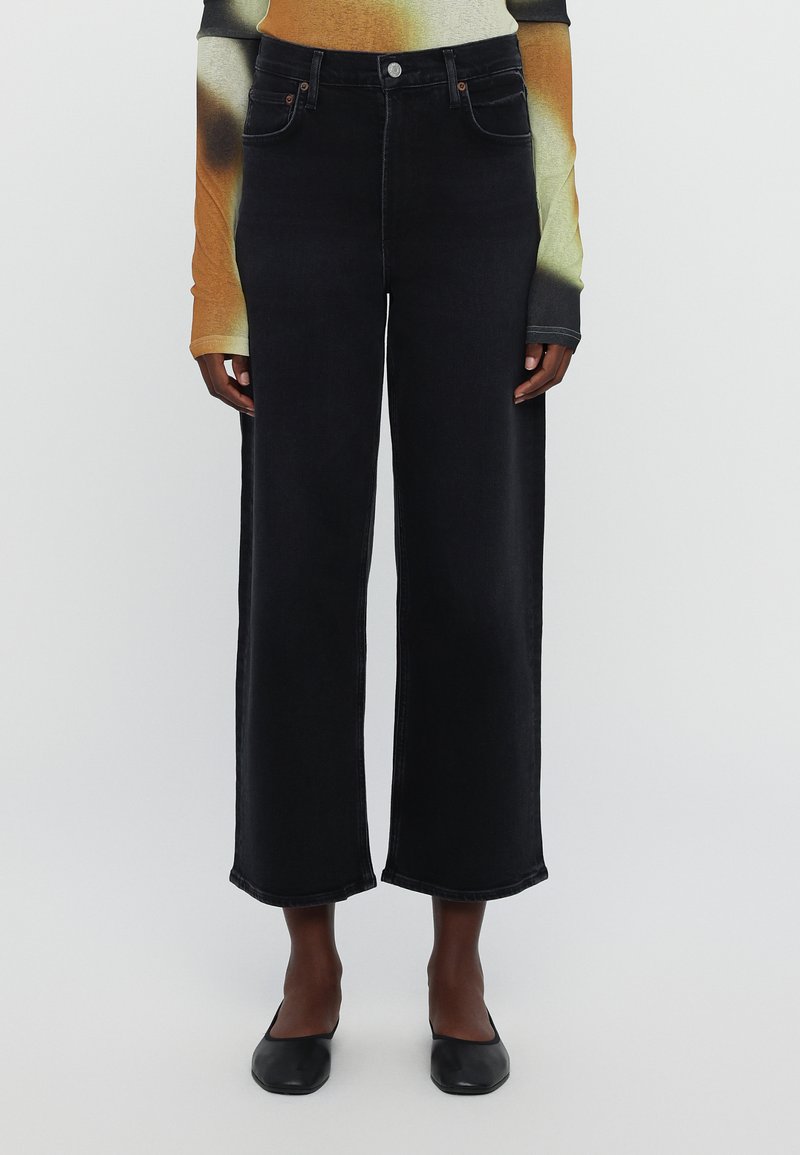 High-waisted, wide-leg black denim jeans with a slightly faded texture. Features five pockets and contrasting stitching.
