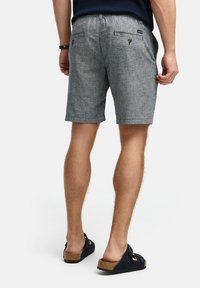 Sivi kratki hlače s teksturom i slim fit krojem, s stražnjim džepovima i gumbima. Upravlja se s tamnim sandalama. Standardna duljina, ležeran dizajn.