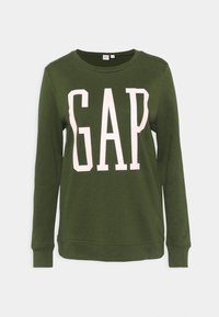 Sudadera de color verde oliva hecha de una tela suave, con cuello redondo y mangas largas. Gran texto "GAP" en blanco en la parte frontal.