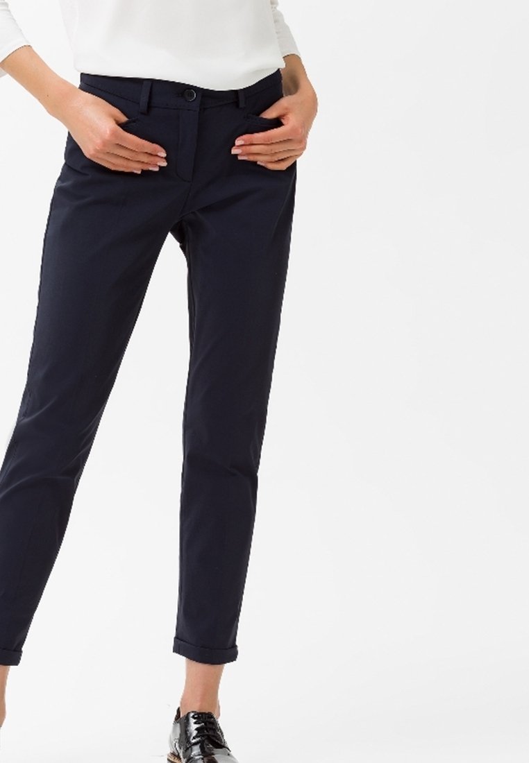 Pantalons bleu marine avec une coupe ajustée, dotés d'un devant plat, de deux poches latérales et de bas de jambes retroussés. Fabriqués dans un tissu lisse et léger.