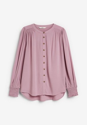 Lichtroze blouse met knopen, lange mouwen, met geplooide schoudernaden en gerimpelde manchetten. Gemaakt van zachte stof met een afgeronde zoom.