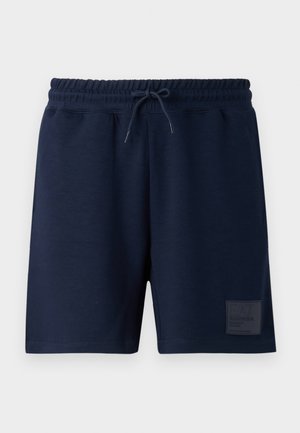 Tumed sinised lühikesed püksid pehmest kangast, millel on elastne vöökoht ja nööriga, ning alumises vasakus nurgas logotäht.