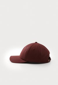 Bordeaux baseballcap laget av bomull, med buet skygge, seks paneler og en knapp på toppen. Justerbar stropp bak.