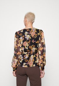 Schwarze, durchsichtige Bluse mit floralen Mustern in Gelb-, Pink- und Orangetönen. Puffärmel mit gerafften Manschetten und einem Taillenbund.