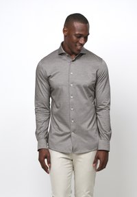 Lichtgrijs overhemd met lange mouwen in een slim fit, met een knoopsluiting aan de voorkant en een soepele, gestructureerde stof. Gecombineerd met lichtgekleurde broeken.