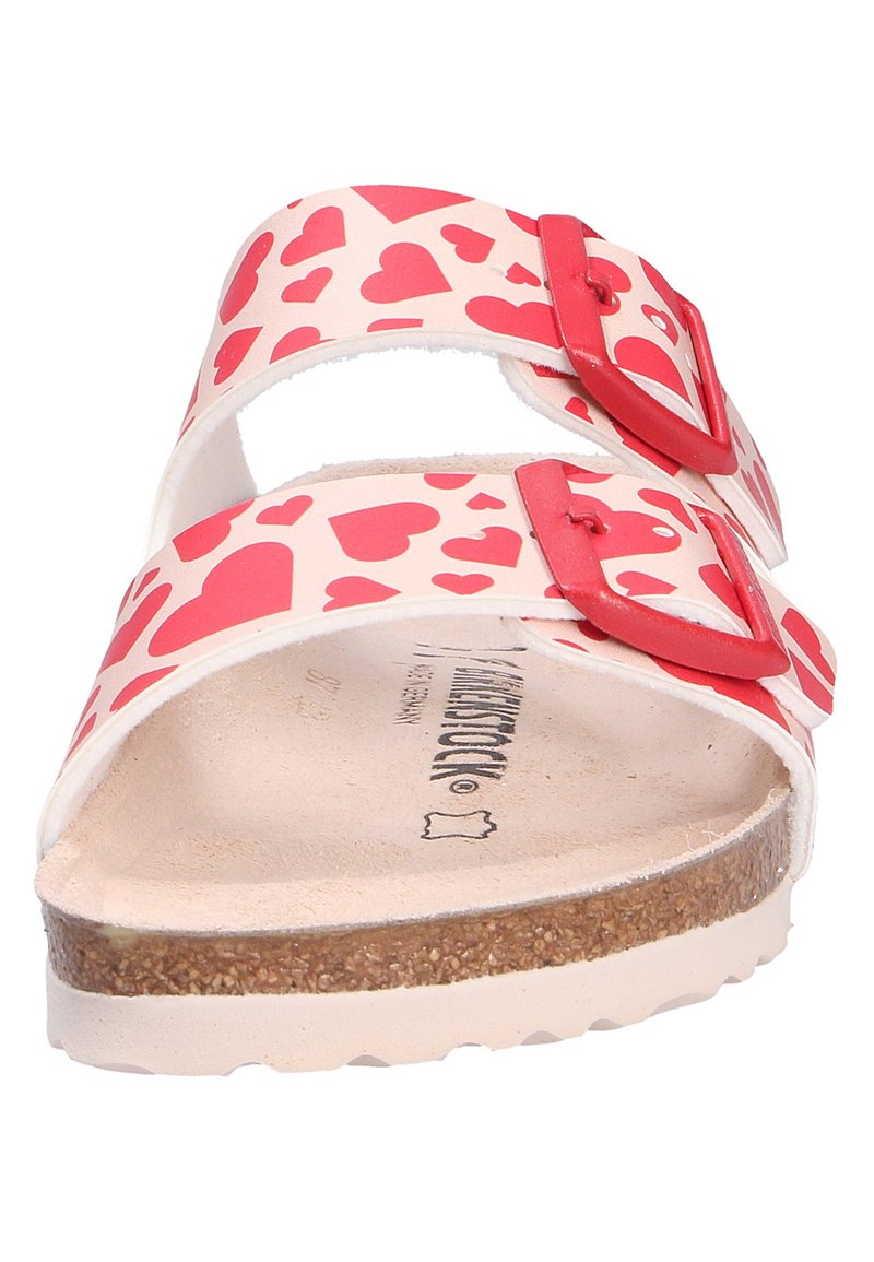 Sandali rossi con motivo a cuore, dotati di due fibbie regolabili rosse. Realizzati in materiale sintetico con una soletta in sughero e suola beige.