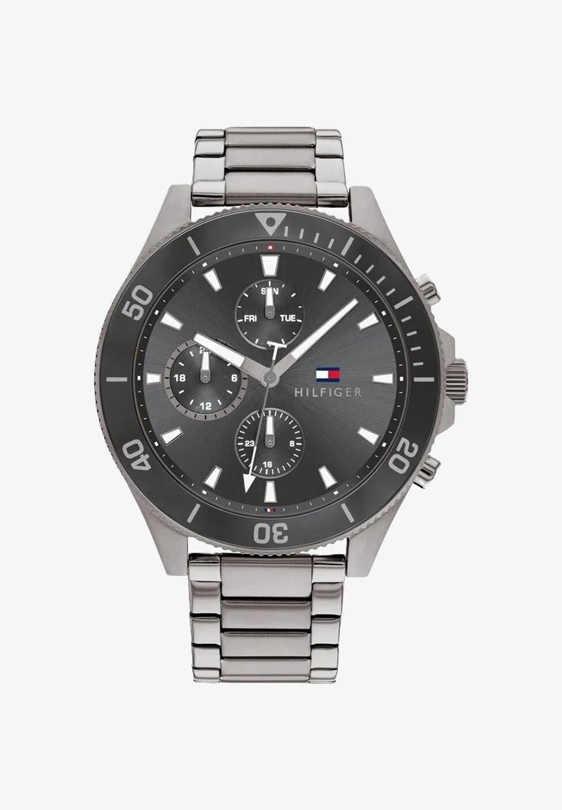 Silver metal wristwatch with black round dial, three smaller dials indicating day, 24-hour time, and seconds, with Hilfiger logo on face.