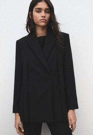 Czarna, dopasowana marynarka o strukturalnym kroju, z jednorzędowym zapięciem, klapami z wycięciami i przednimi kieszeniami. Gładka tekstura z mieszanki wełny.