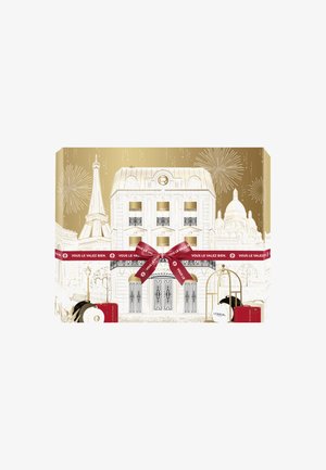 Un bâtiment de style parisien enveloppé d'un ruban rouge et d'un nœud, présentant des produits de soin de L'Oréal Paris et des feux d'artifice dans une palette de couleurs dorée et blanche.