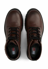 Braune Leder-Ankle-Boots mit schwarzen Schnürsenkeln, runder Zehenpartie, schwarzer Gummisohle, Kontrastnähten und markiertem Innensohlen-Detail.