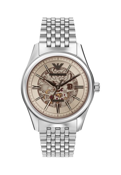 Montre automatique en argent avec un cadran beige transparent dévoilant une mécanique complexe, des index horaires fins et un bracelet en maille métallique poli.