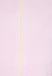 Indumento di colore rosa chiaro con una zip bianca ben visibile, texture liscia e design minimalista. Adatto per abbigliamento casual o sportivo.