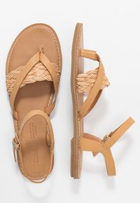 Lysebrune sandaler med flettede remme og flade såler. Lædermateriale, sidespænde og syningsdetaljer fremhæver designet.