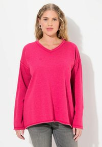 Sudadera de cuello en V fucsia con mangas largas, con un corte relajado y dobladillo sin rematar. Patrón de estrellas sutiles en toda la tela.