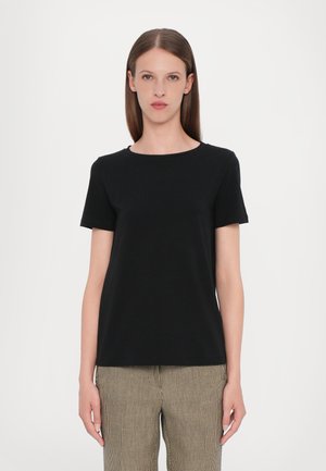 T-shirt noir à manches courtes avec un col rond, fabriqué à partir d'un tissu lisse. Associé à un pantalon à carreaux beige et noir avec un motif.