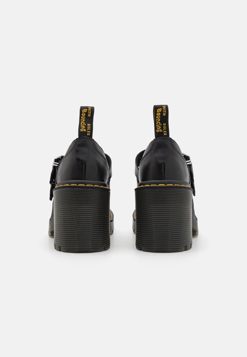 Schwarze Leder-Plateauschuhe mit einem dicken, gerippten Absatz und kontrastierenden gelben Nähten. Sie verfügen über einen Riemen mit einer Schnalle und einer Zuglasche.