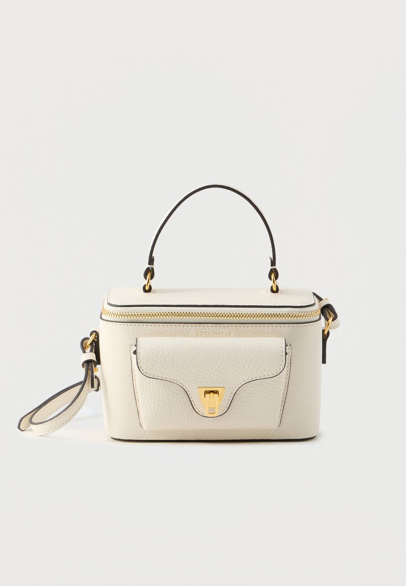 Borsa in pelle color crema con manico superiore, dettagli dorati, chiusura con zip e tasca frontale. Presenta rifiniture nere e base piatta per maggiore stabilità.