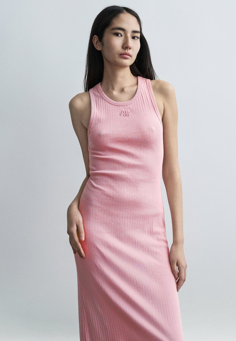 Ροζ ριμπ φόρεμα με εφαρμοστή σιλουέτα. Διαθέτει στρογγυλή λαιμόκοψη και διακριτική λεπτομέρεια λογότυπου στο στήθος. Μαλακή υφή, μήκος μέχρι τον αστράγαλο.