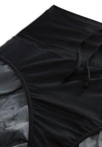 Bas de bikini noir taille haute avec empiècements en mesh et détail cordon, posé à plat sur fond blanc.