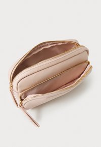 Portefeuille zippé rose clair en matériau texturé. Il dispose de deux compartiments doublés d'un tissu lisse et de zips dorés.