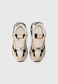 Beige og svarte sneakers med mesh- og suede-overdel, rund tå og hvite snørebånd. Pyntet med en logo på tungen og hælen.