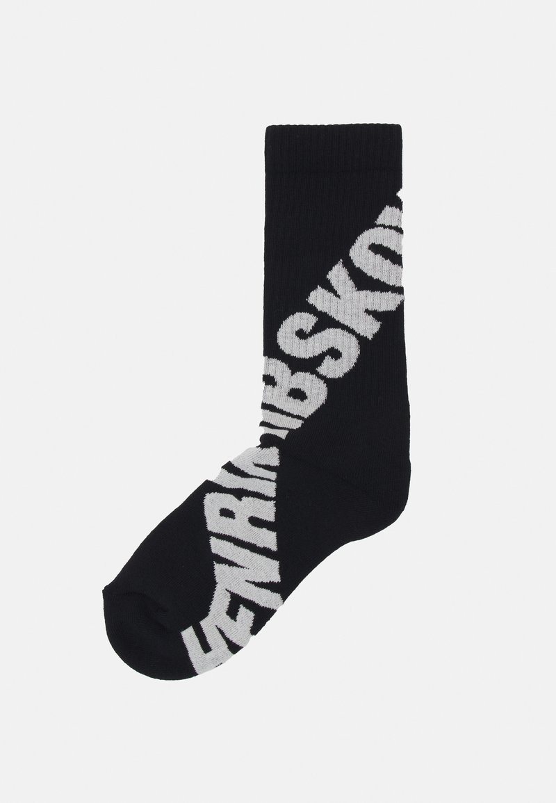 Black sock with large white diagonal lettering. Material appears knitted, featuring a reinforced heel and toe.